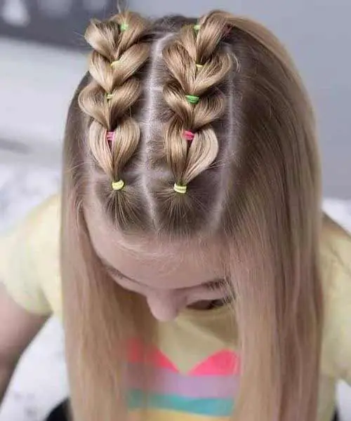 Peinado infantil con coletas trenzadas con gomas de pelo y el cabello suelto