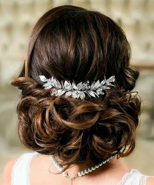 Peinado de estilo elegante con ondas en el pelo y una horquilla de flores