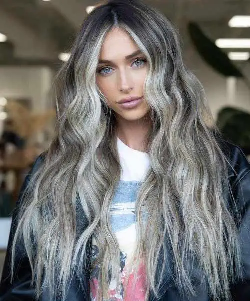 Mujer con el pelo bonito con ondas y mechas balayage de color platino y rubio claro ceniza
