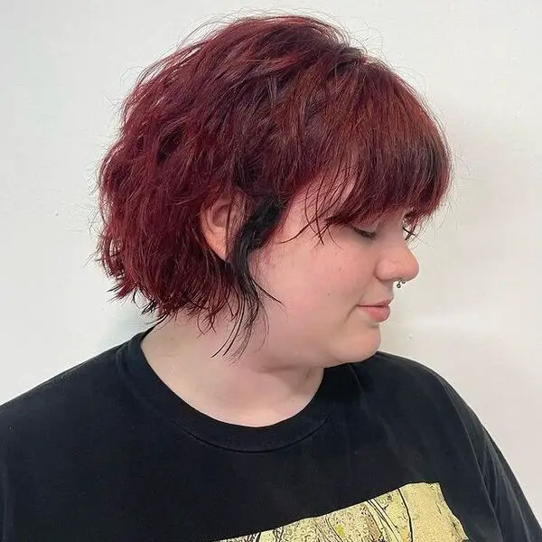 pelo rojo oscuro - una chica con un piercing en la nariz y viste una camisa negra estampada