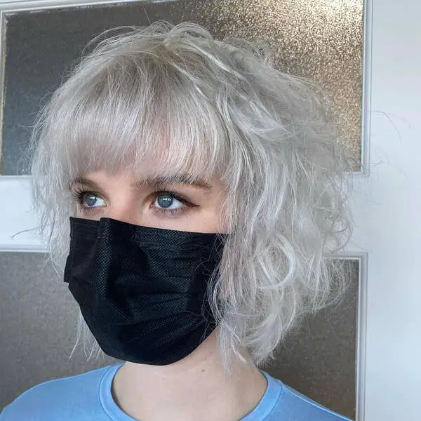 Icy Blonde with Layered Bob: una mujer con una camisa azul y una máscara negra