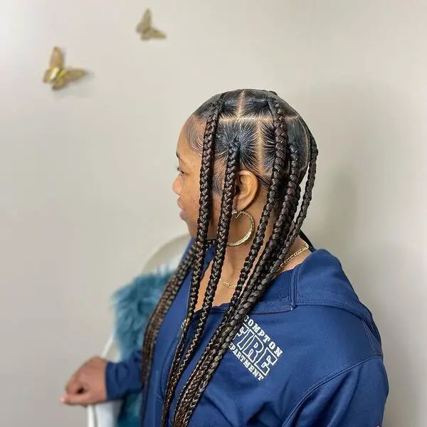 Trenza Jumbo Knotless: una mujer con una chaqueta de color azul y aretes dorados con un gran círculo