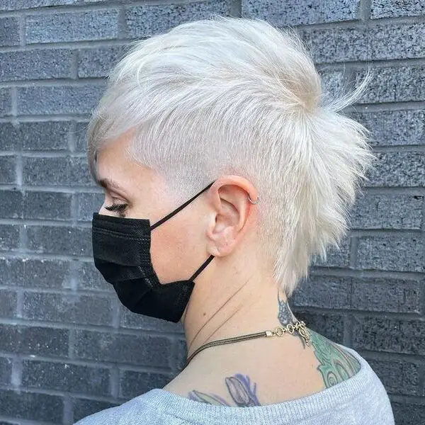 Platinum Fauxhawk Pixie Cut: una mujer con un tatuaje que lleva una máscara negra