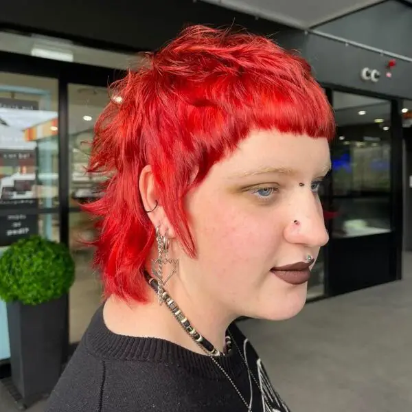 Corte de pelo vanguardista de salmonete: una mujer con muchos aretes y collar