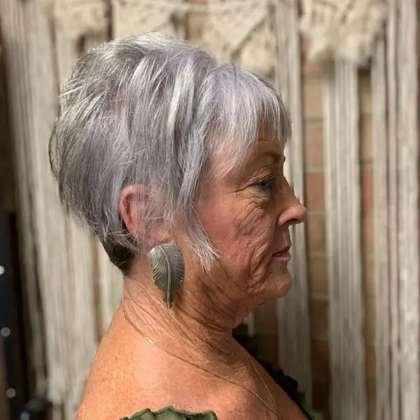 Sassy Pixie Cut - an old woman wearing a metallic leaf earrings.