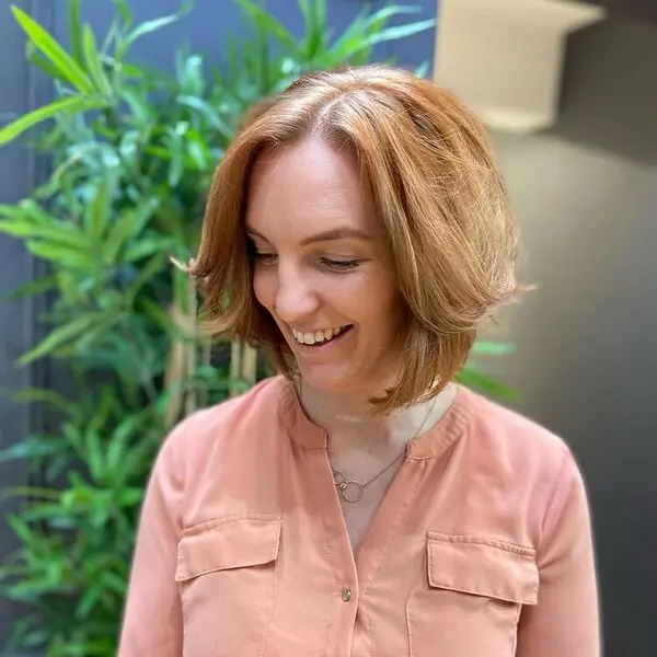 Peinado hinchable y que enmarca la cara: una mujer sonriendo y con una blusa color melocotón