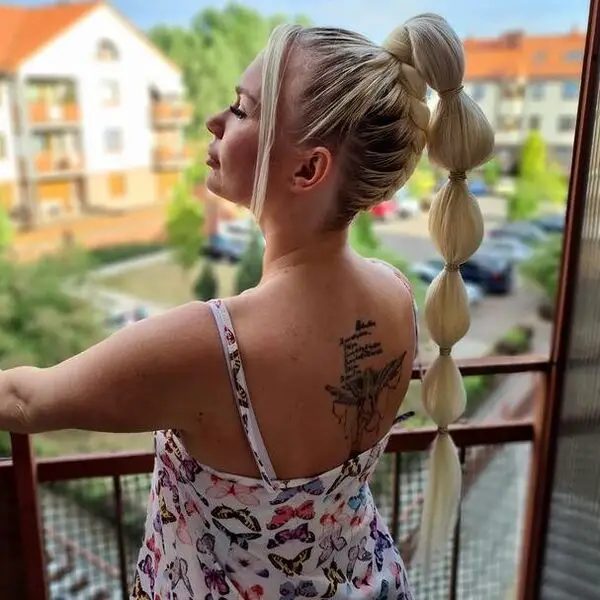 Cabello largo con media trenza Trenzas de burbujas: una mujer con un tatuaje que lleva una camisa sin mangas con una mariposa impresa