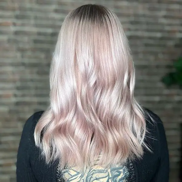 una mujer con una manga larga negra tiene un hermoso corte de pelo rosa pastel champán