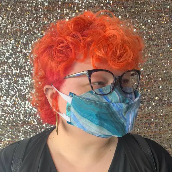 Curl Mullet en Vibrant Orange: una mujer con una colorida máscara de algodón y anteojos.
