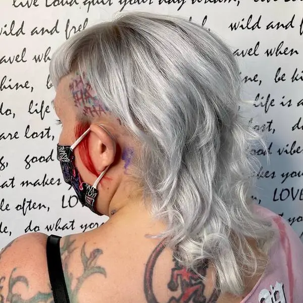 Icy Blonde with Lightly Shagged Mullet: una mujer que lleva un top sexy con un tatuaje en la cabeza y la espalda.
