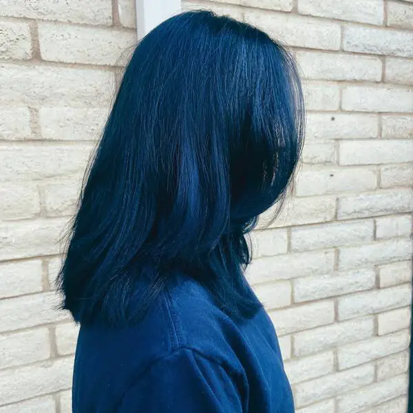 Longitud media con cabello negro azulado: una mujer con una camisa azul