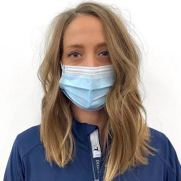 una mujer con mascarilla quirúrgica con una chaqueta azul