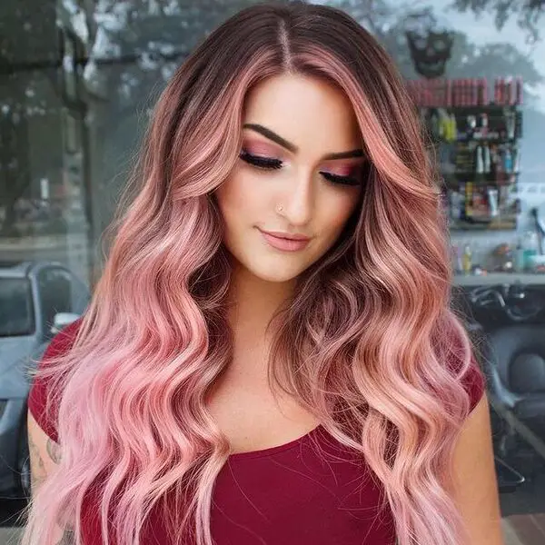 una mujer con un croptop granate tiene un cabello balayage rosa pastel