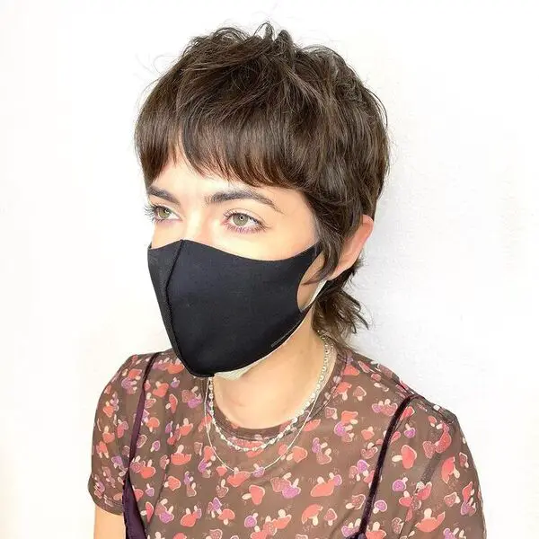 Pixie Mullet con flequillo de cortina corto: una mujer con una camisa estampada y una máscara negra