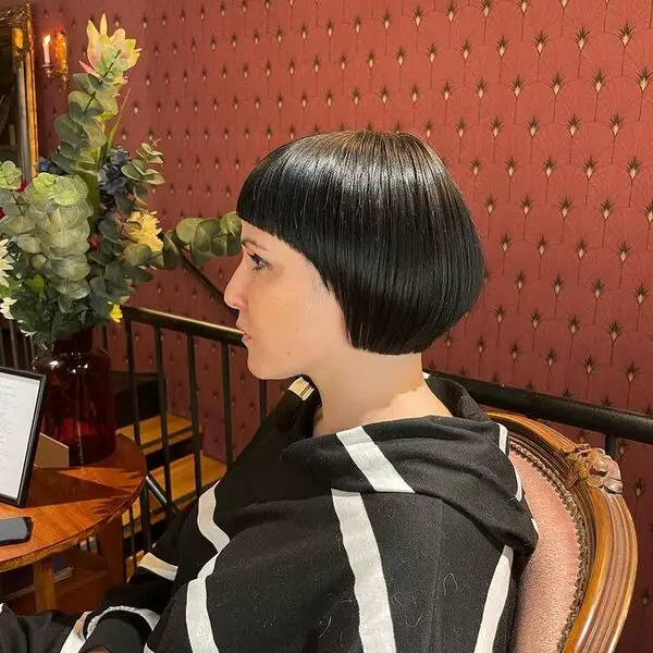 Corte de pelo Bob corto con flequillo corto: una mujer sentada con una chaqueta blanca y negra