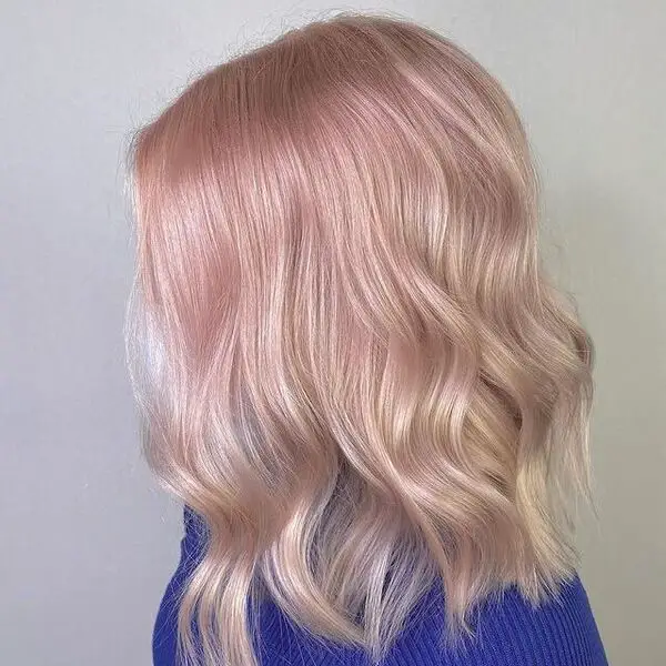 una mujer con una manga larga azul tiene un peinado de color rosa pastel suave 