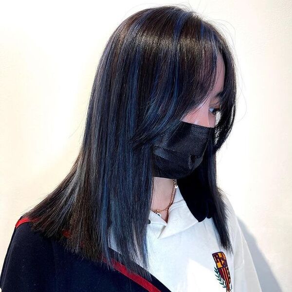 una mujer con una máscara facial negra tiene un cabello azul sutil